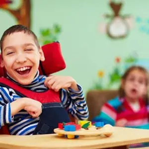 A happy boy in a wheelchair smiling and laughing in a rehabilitation center