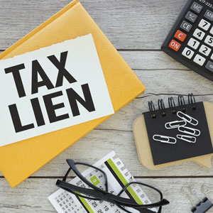 Tax lien notice with calculator and documents on desk, handling tax-related legal matters.