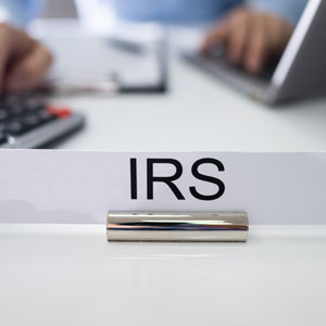 IRS sign with person calculating and typing, depicting IRS garnishment for gig workers.  