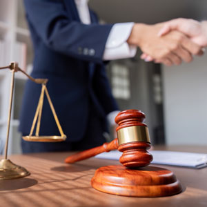 A gavel, scales of justice, and a handshake, depicting legal action against a trustee. 