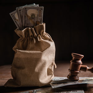 A burlap bag full of money next to a gavel, representing financial settlements in a legal case. 
