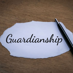 A pen rests on a torn piece of paper with the word "Guardianship" written on it. 