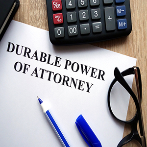 Durable power of attorney document with pen, glasses, and calculator on a desk.