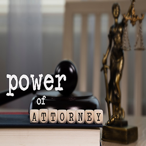 Words POWER OF ATTORNEY composed of wooden dices. Wooden gavel and statue of Themis in the background. Closeup