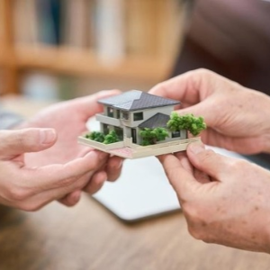 Businessman holding a miniature house representing newly discovered estate assets